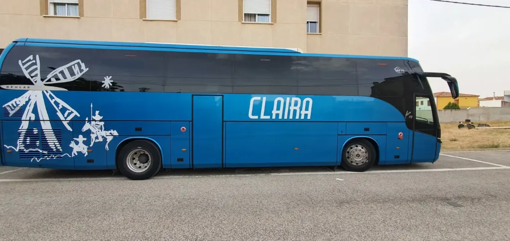 Autobús azul de Viajes Claira con ilustración de Don Quijote y molino de viento, preparado para excursiones organizadas en Castilla-La Mancha.