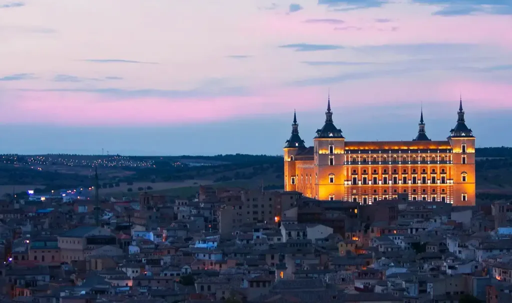 Vista panorámica de Toledo al atardecer con el Alcázar iluminado, una de las joyas históricas visitadas en las rutas organizadas por Viajes Claira.
