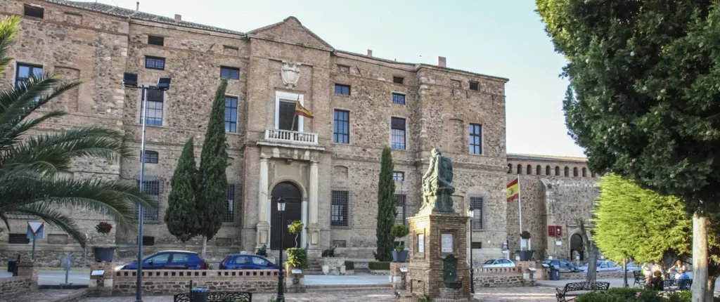 Fachada lateral del Palacio del Marqués de Santa Cruz en Viso del Marqués, con jardines y la estatua de Álvaro de Bazán, parada esencial en las excursiones culturales de Viajes Claira.