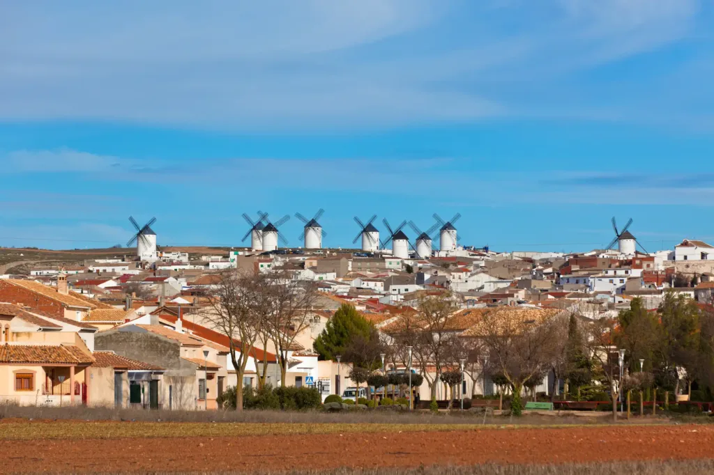 Vista panorámica de Campo de Criptana con sus emblemáticos molinos de viento sobre la colina, símbolo de la Ruta del Quijote en Castilla-La Mancha.
