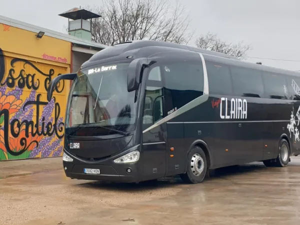 Autobús de Viajes Claira en Ossa de Montiel junto a mural turístico, punto de inicio para excursiones organizadas por La Mancha.