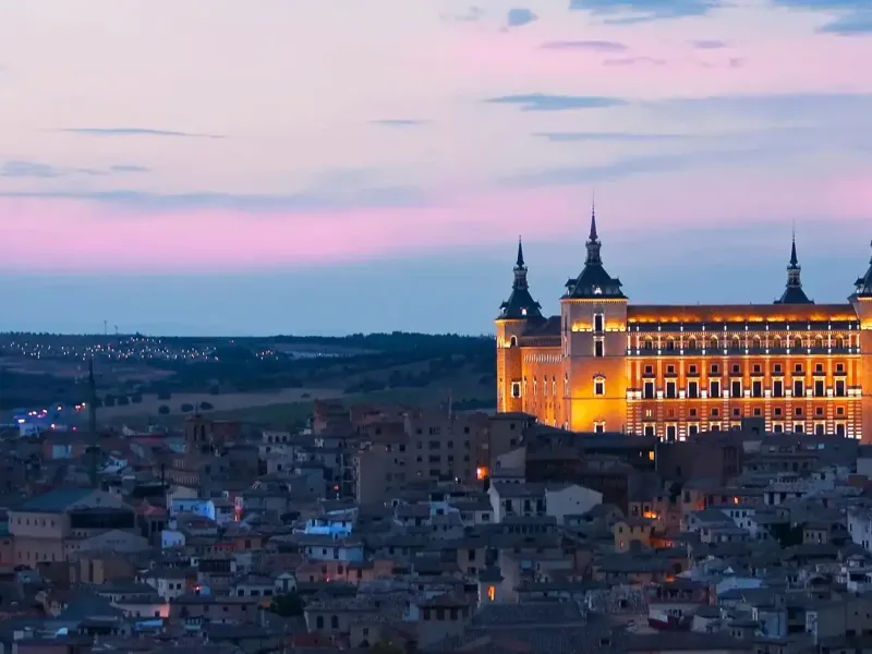 Vista panorámica de Toledo al atardecer con el Alcázar iluminado, una de las joyas históricas visitadas en las rutas organizadas por Viajes Claira.